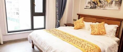 A hotel room with a large bed, a window with curtains, a painting on the wall, and a wooden nightstand.