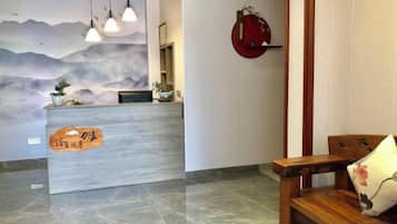 Un mostrador de recepción con un mural, un banco de madera y un objeto circular rojo en la pared.