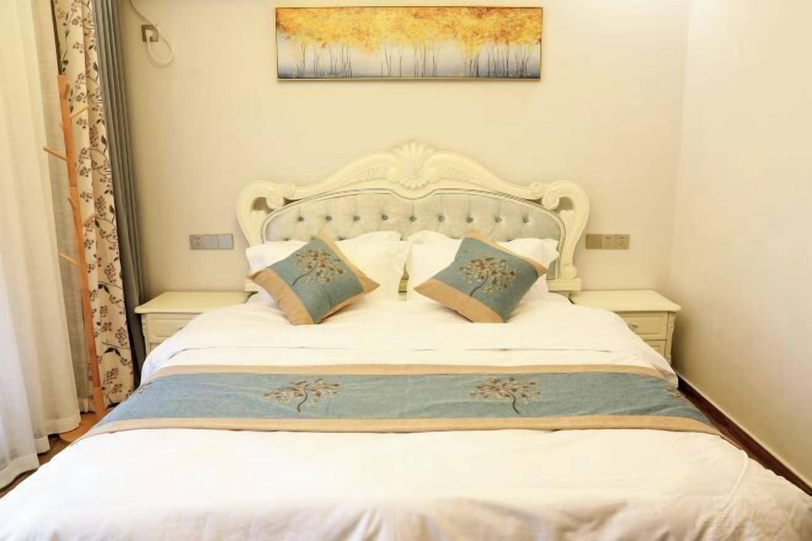 Una cama bien hecha con un cabecero decorativo, una mesita de noche y un cuadro colgado en la pared.