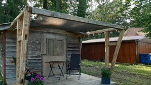Une cabane en bois rustique, dotée d’une véranda, d’une porte et d’une petite table avec deux chaises.