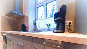 Une cuisine moderne dotée d’appareils électroménagers en acier inoxydable, d’une fenêtre donnant sur les arbres et d’une machine à café posée sur le plan de travail.