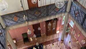 Een meerlaagse hotel lobby met een centraal zithoek, een houten kast en hangende verlichtingsarmaturen.