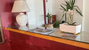 Een receptiebalie met een glazen blad, een witte lamp en diverse planten.