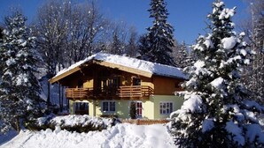 Una cabaña de madera con balcón, rodeada de árboles cubiertos de nieve.