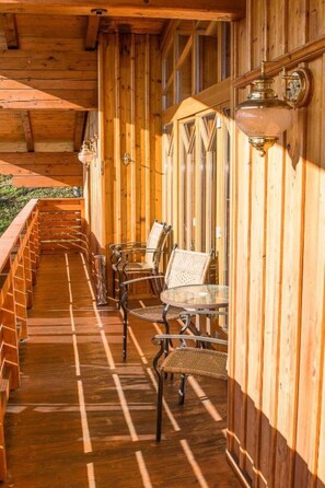 Una terraza de madera con mobiliario exterior y barandilla.