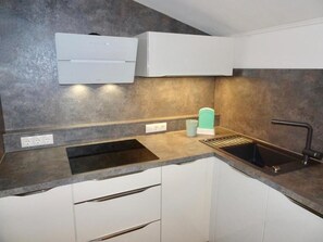Een moderne keuken met een ingebouwde vaatwasser, een spoelbak en een aanrecht met een koffieapparaat.