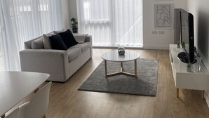 Un saló modern amb un sofà, una taula de centre, un moble de televisió i una zona de menjador.
