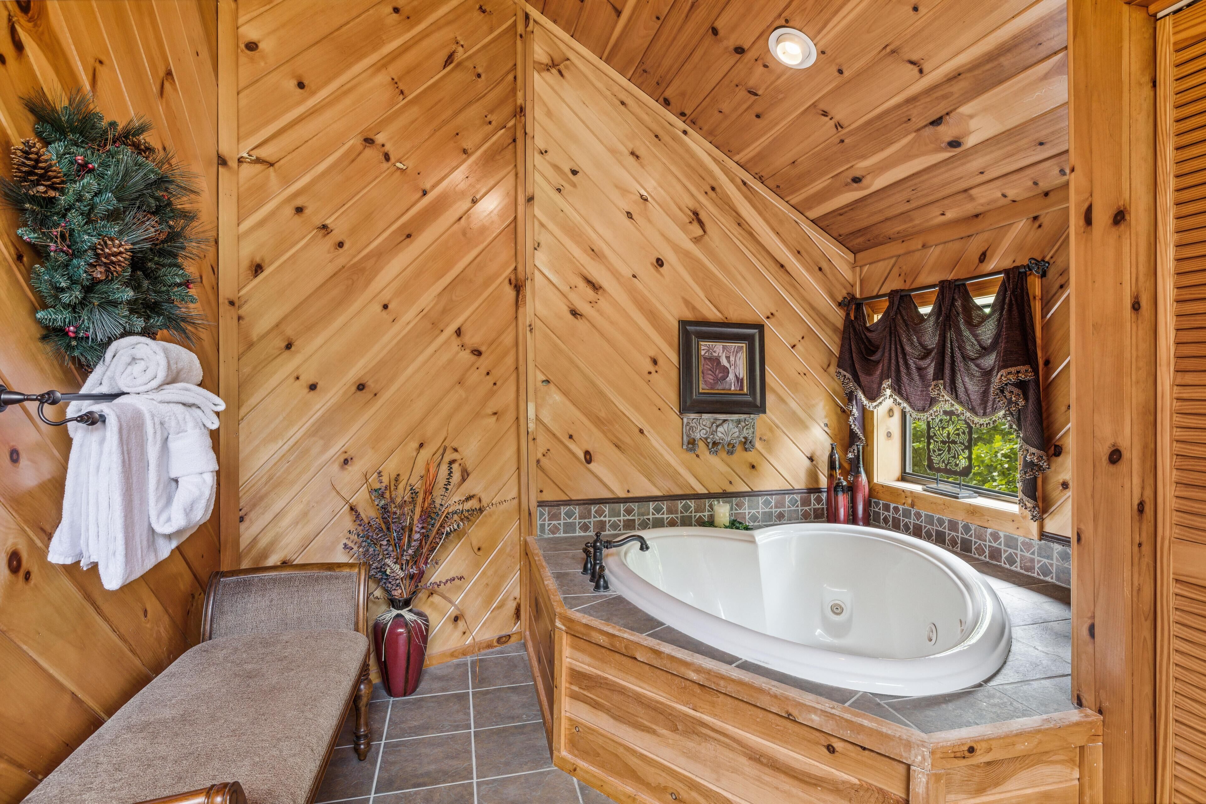 A wooden cabin bathroom with a bathtub, a bench, a towel rack, and a decorative wreath.