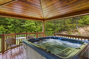 Ein Whirlpool auf einer Holzdiele mit Blick auf einen Wald.