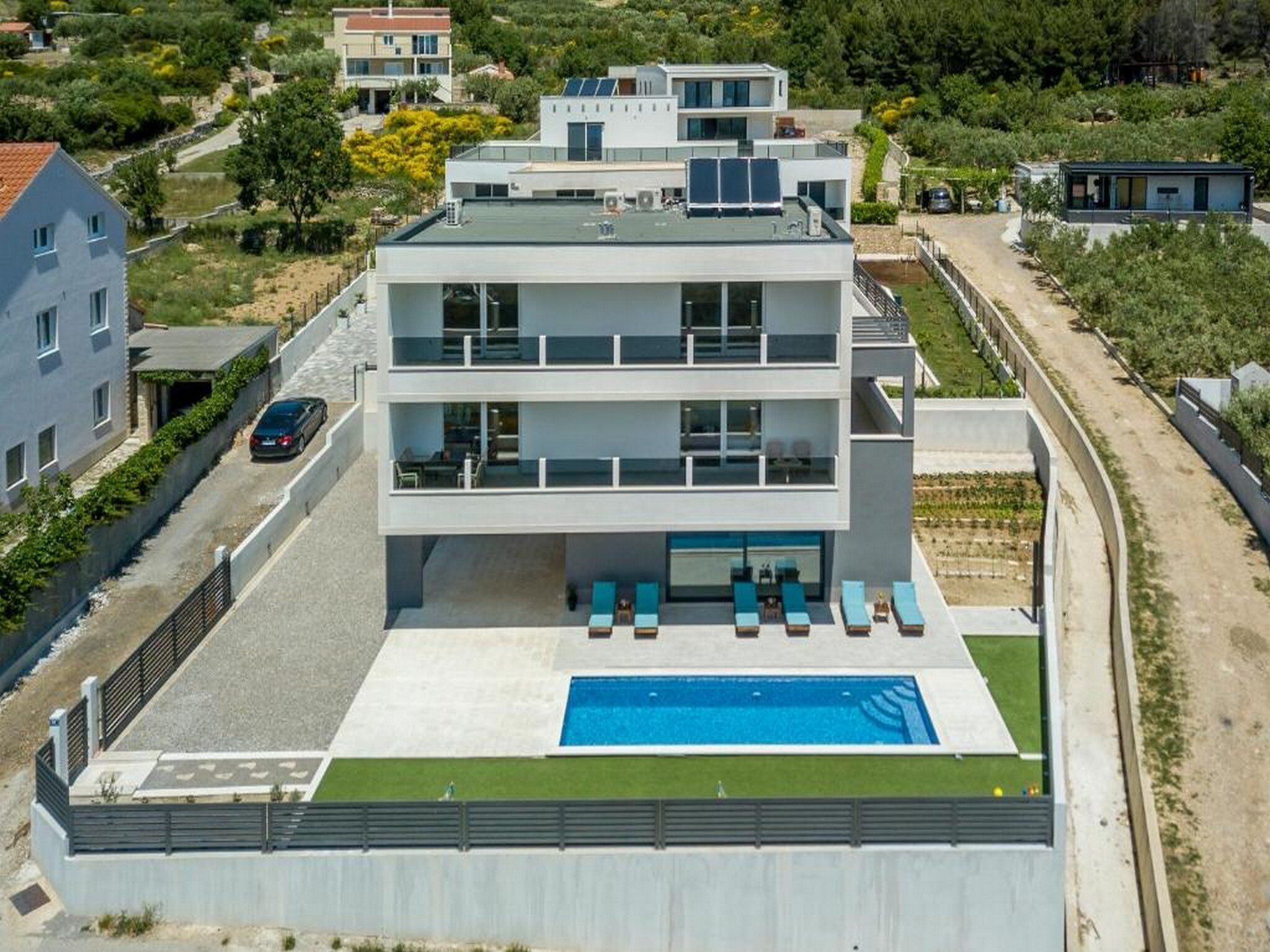 Un edificio moderno de varios pisos con piscina en la azotea, un espacio al aire libre techado con asientos y vistas del paisaje circundante.