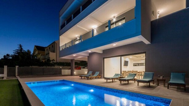 A modern two-story building with a swimming pool and outdoor seating area.