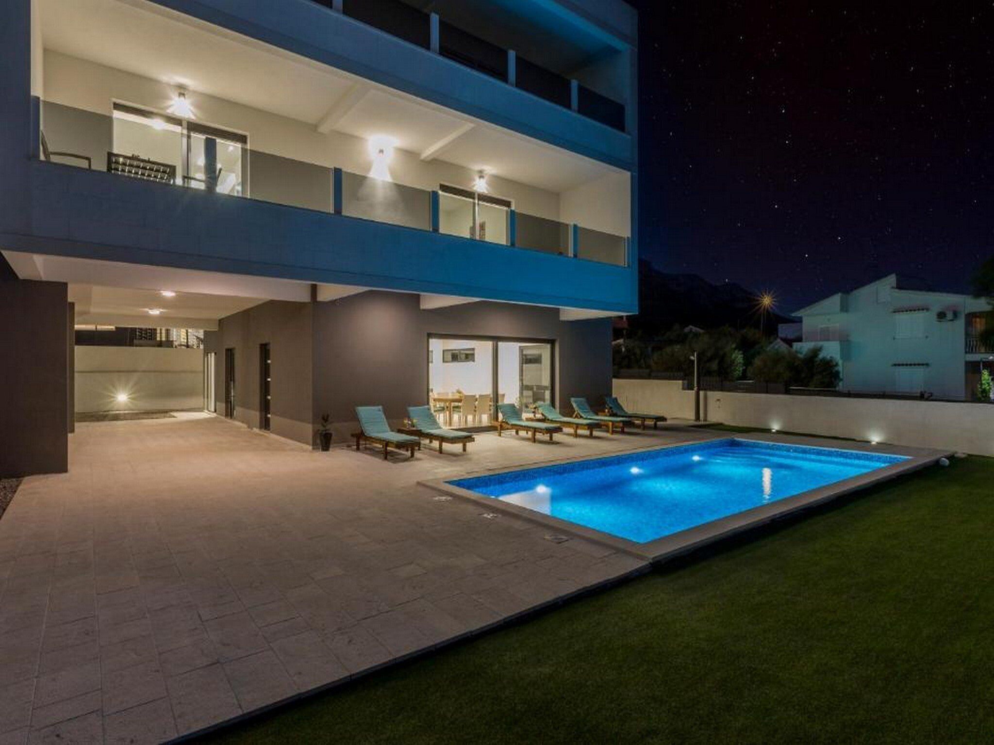 Un bâtiment moderne à deux étages, doté d’une piscine, d’un espace extérieur aménagé et d’un balcon bien éclairé.