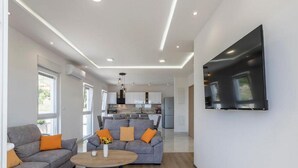 A modern living room with a grey sofa, a coffee table, and a TV mounted on the wall.