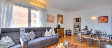 Uma sala de estar com sofá, mesa de centro e área de jantar com mesa e cadeiras.