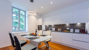 A modern kitchen with white cabinets, a dining table with chairs, and a large window. - Love of Lugano in Lugano (Lugano)