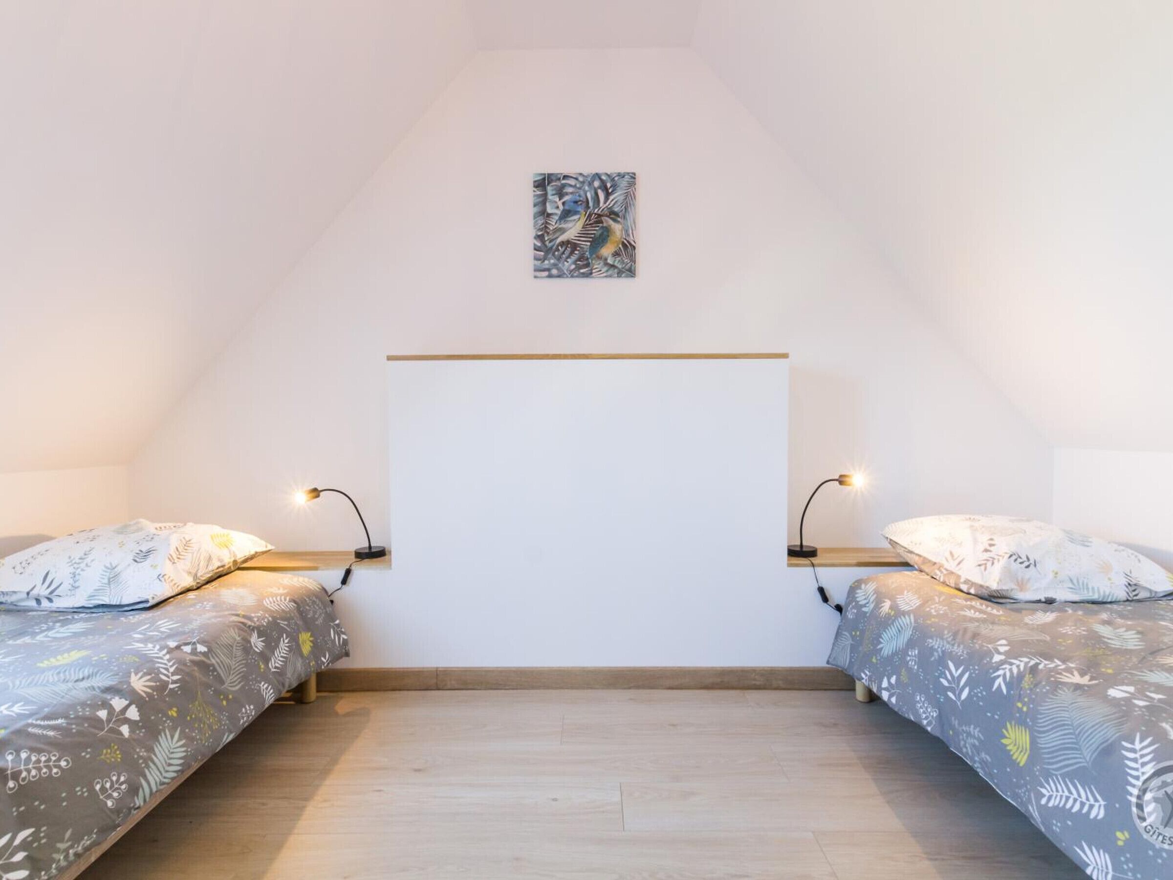 Una camera da letto con due letti, una testiera in legno, un piccolo quadro e lampade da comodino.