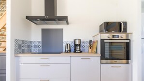 Een moderne keuken met witte kasten, een roestvrijstalen oven, een magnetron en een koffiezetapparaat.