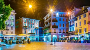 A brightly lit square with historic buildings, outdoor seating, and a visible restaurant named 'Café'. - Fairy Home in Viganello Lugano (Lugano)
