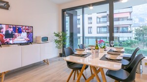 A modern dining area with a large window, a television on the wall, and a dining table set for two. - Fairy Home in Viganello Lugano (Lugano)