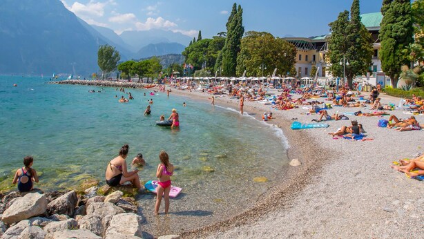 Une plage à l’eau claire, avec un rivage rocheux, où les gens profitent du soleil.