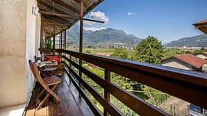 Un balcon en bois offrant une vue sur les montagnes et un village.