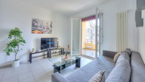 A modern living room with a sofa, a glass coffee table, a TV, and a potted plant. - Central Amor in Lugano (Lugano)
