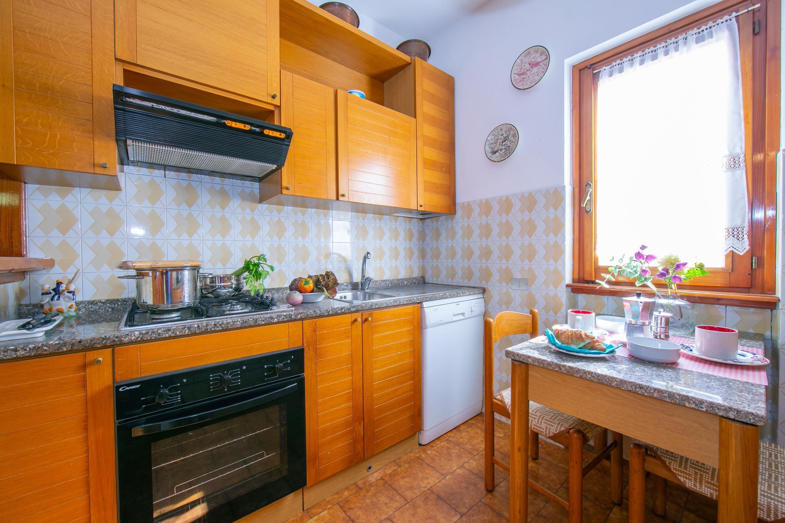 Une cuisine dotée de meubles en bois, d’une cuisinière, d’un lave-vaisselle et d’un coin repas avec une table et des chaises.