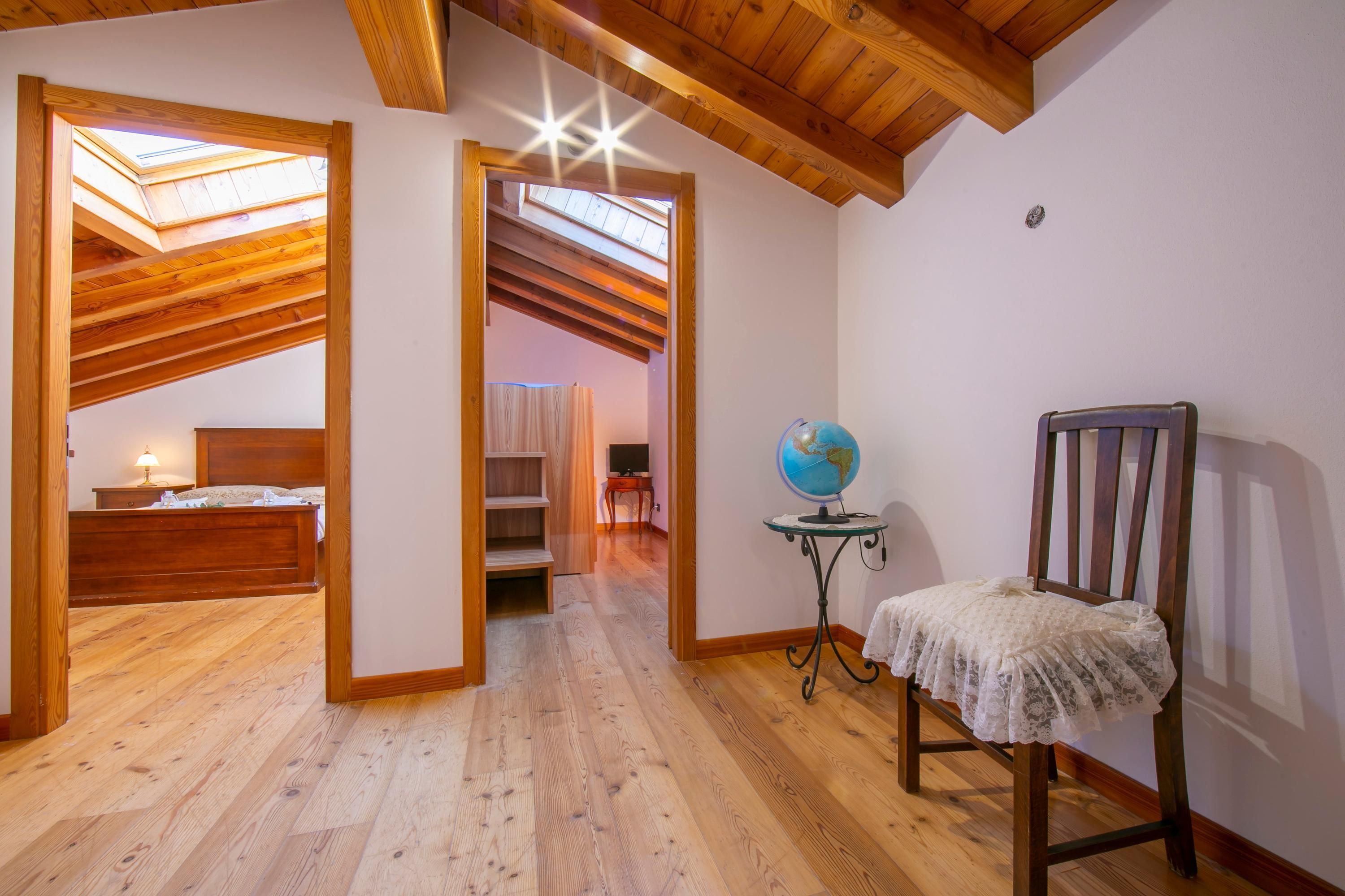 Une pièce avec un plancher en bois, un lit, une chaise et un globe terrestre posé sur une petite table.