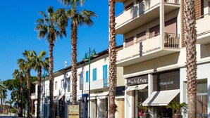 A street lined with palm trees and multi-story buildings with storefronts.