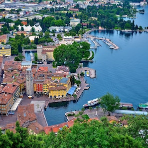 A riverside town with historic buildings, a prominent clock tower, and a marina with boats. - Casa Turchese in Riva del Garda (Riva del Garda)