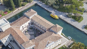 Vista aèria d'un edifici històric amb un pati central, envoltat d'aigua i vegetació.