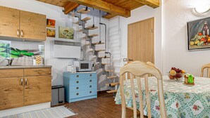 Una cocina acogedora con armarios de madera, un aparador azul, una mesa de comedor con mantel floral y una escalera de caracol.