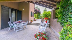 A covered patio with a table and chairs, a potted plant, and a flower arrangement. - Residenza La Parusciola (Gignese)