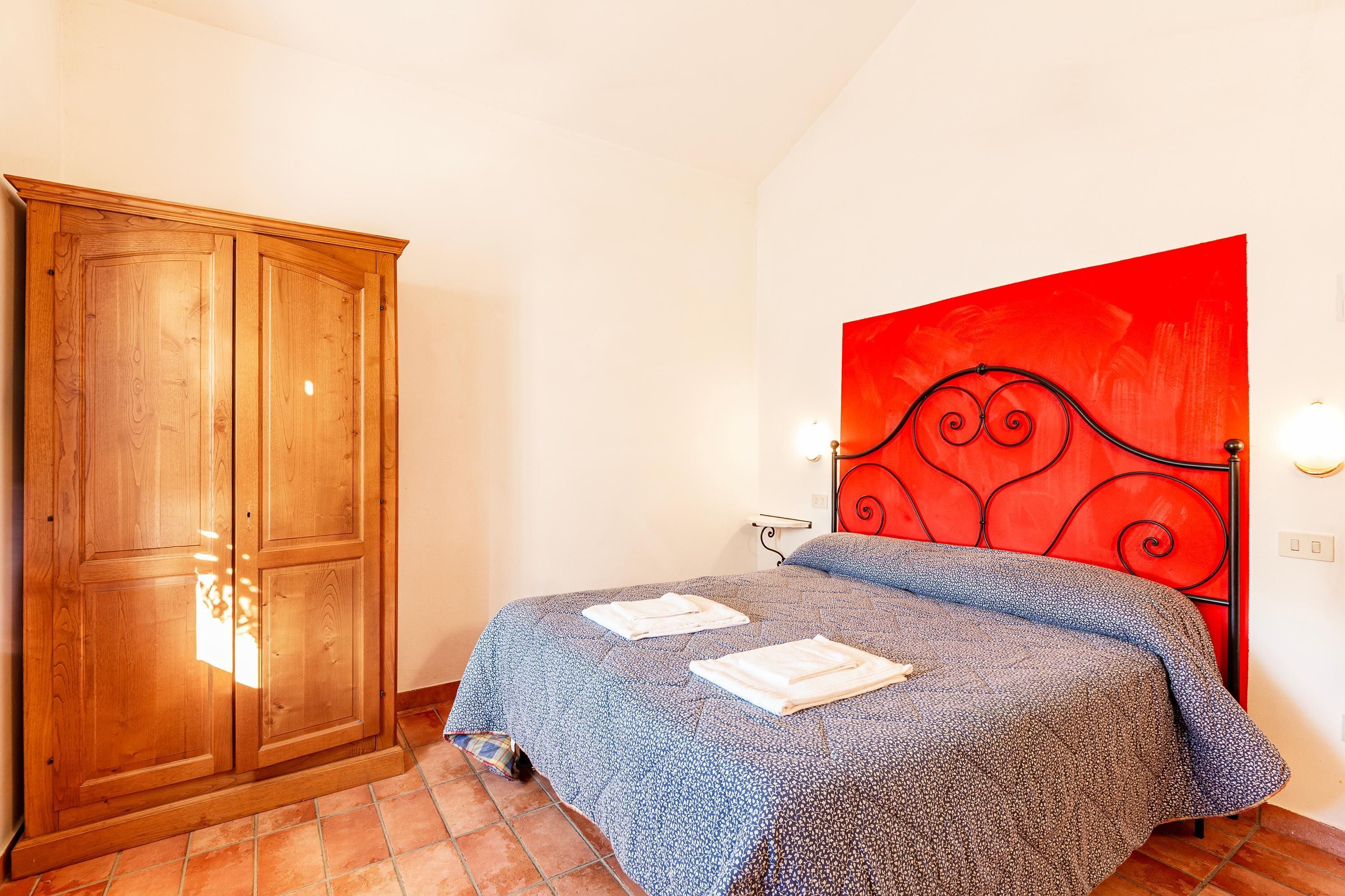 Ein Schlafzimmer mit Bett, Schrank und einer roten Akzentwand.
