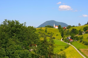 A rural landscape with rolling hills, a church, and scattered houses.