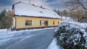En gul bygning med rødt tegltag, omgivet af sne.