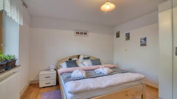 A neatly arranged bedroom with a wooden bed, bedside tables, a nightstand, a radiator, and a wardrobe.