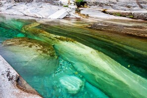 Une piscine aux eaux turquoise et limpides, bordée de gros rochers et d’une rive rocheuse.