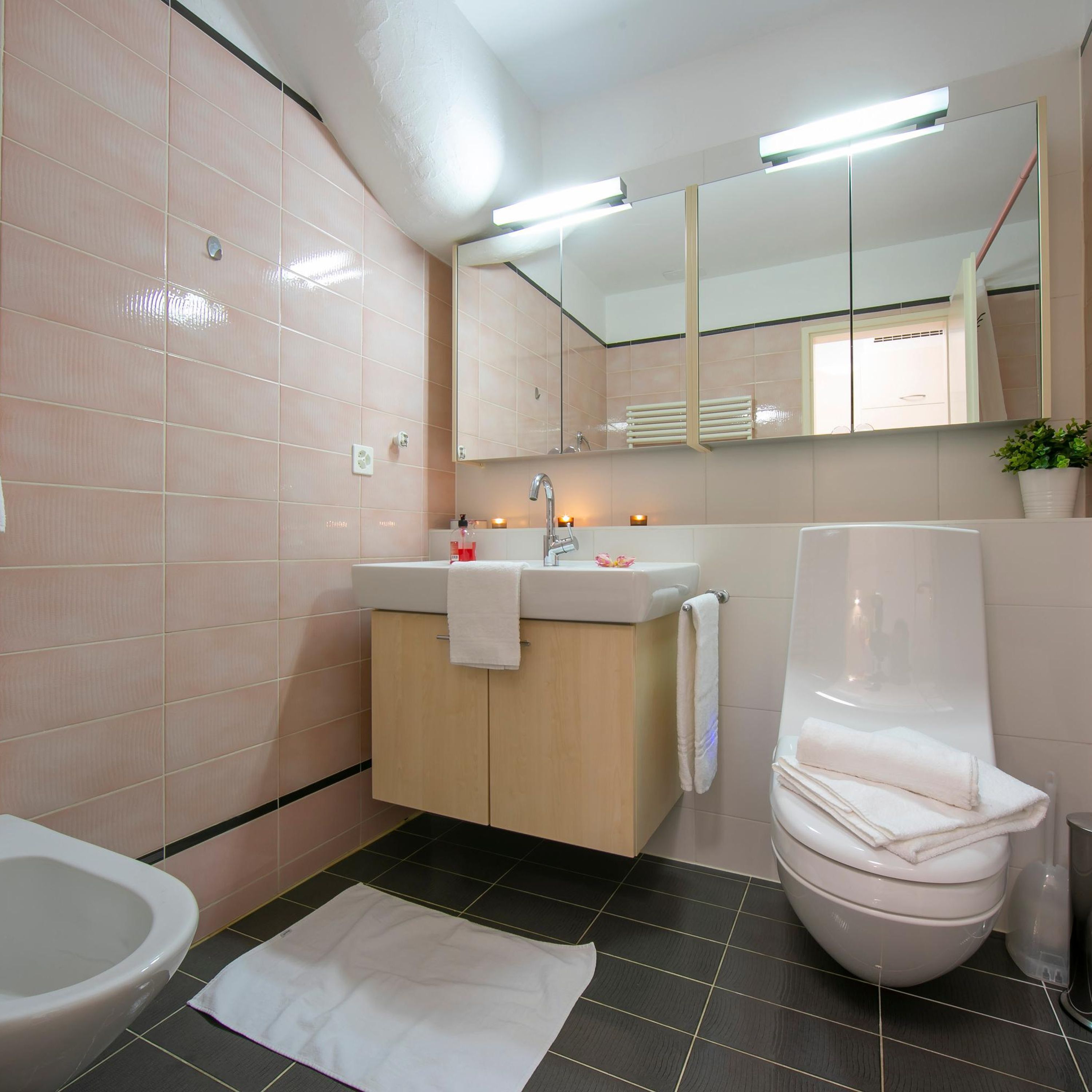 Un baño moderno con inodoro, lavamanos y espejo.