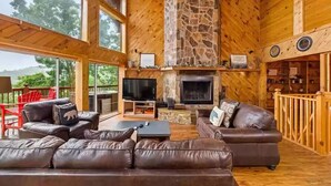 A spacious living area with a stone fireplace, leather sofas, and a television. - Big Sky Lodge #438 (Sevierville)