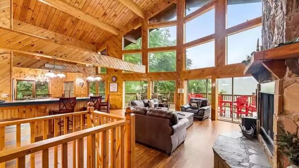 A spacious wooden interior with a high ceiling, large windows, a fireplace, and a cozy seating area. - Big Sky Lodge #438 (Sevierville)