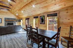 A wooden cabin interior with a dining table, chairs, a sofa, and a fireplace. - Wilderness Waterland #2161 (Sevierville)