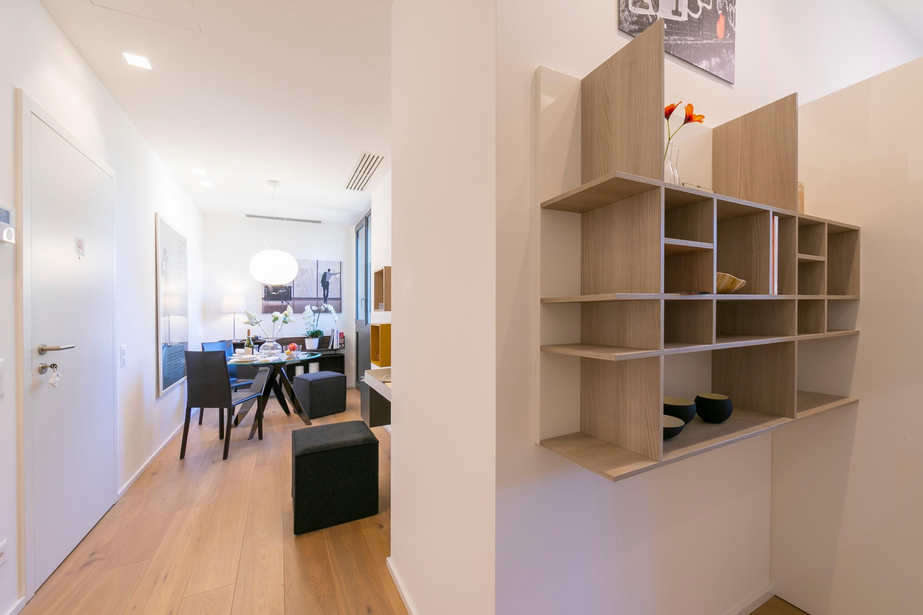 Ein modernes Interieur mit Essbereich, einem Holzregal und einem Flur zu einem anderen Raum.