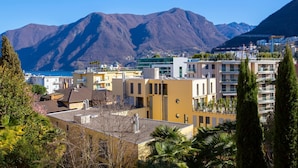 A coastal town with modern buildings, a mountain backdrop, and a clear sky. - Casa Basilico in Lugano (Lugano)