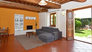 Una sala de estar con un sofá gris, una mesa de centro de madera, un televisor y un mueble frente a una pared naranja.
