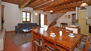 Amplia sala de estar con una mesa de comedor de madera, sofá y una escalera que conduce a otro nivel.