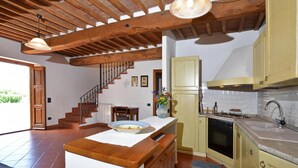 Una cocina amplia con vigas de madera, una isla central y horno empotrado.
