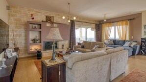 Een woonkamer met een stenen muur, een open haard, een bank en een televisietoestel.