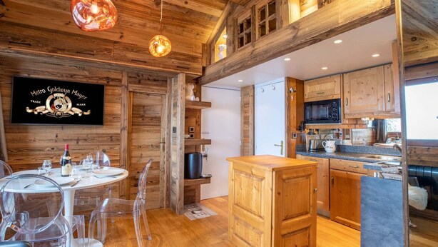 Interior de madera con comedor, cocina y un cartel que dice 'Metro Goldwyn Mayer Trade Mark'.