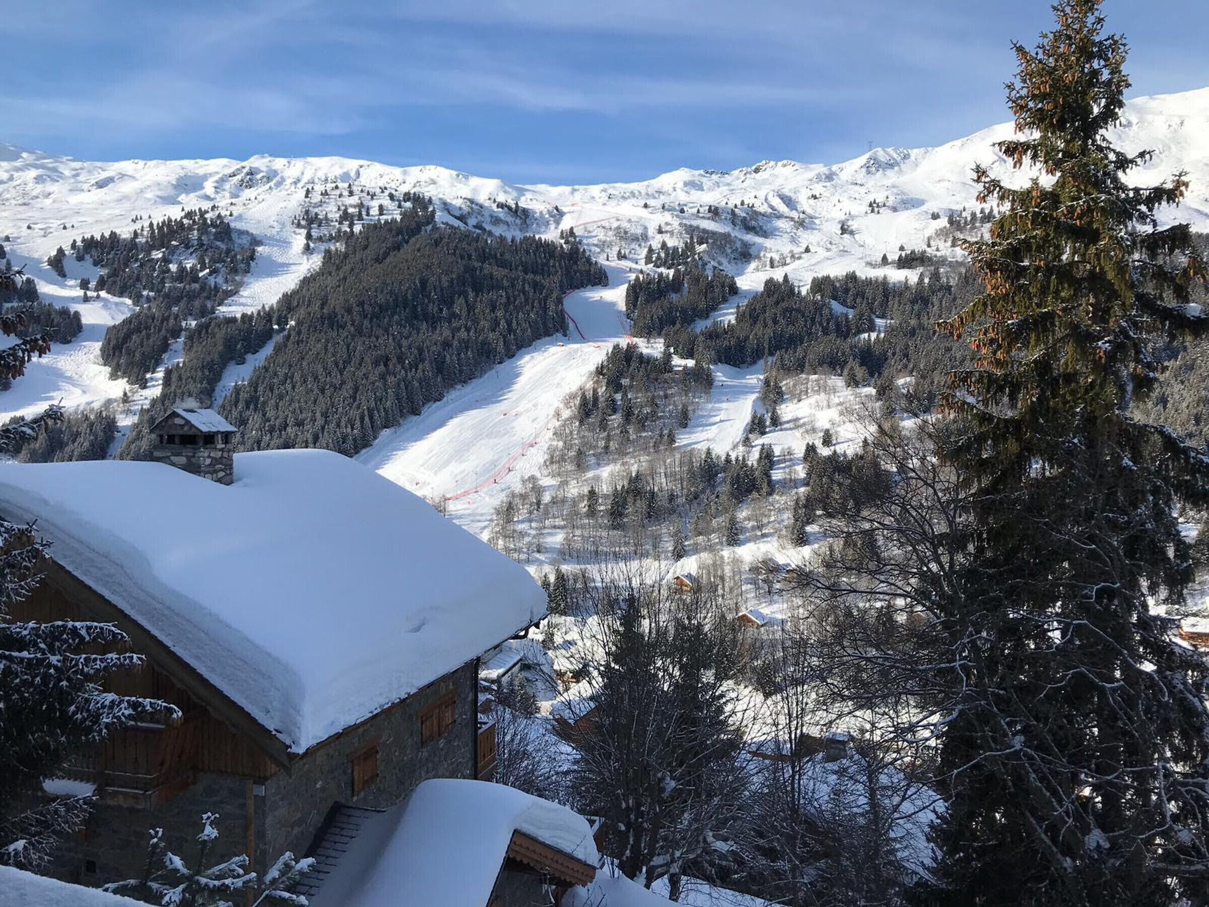 A snow-covered mountain landscape with a wooden cabin and a ski slope.